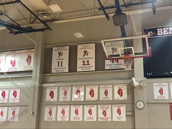 Kathleen Doyle, a 2024 inductee to the ESCC Hall of Fame, is one of the three jerseys retired from use in Benet Academy athletics, a fact demonstrated by the placement of a sign on the wall of St. Ronald's Gymnasium.